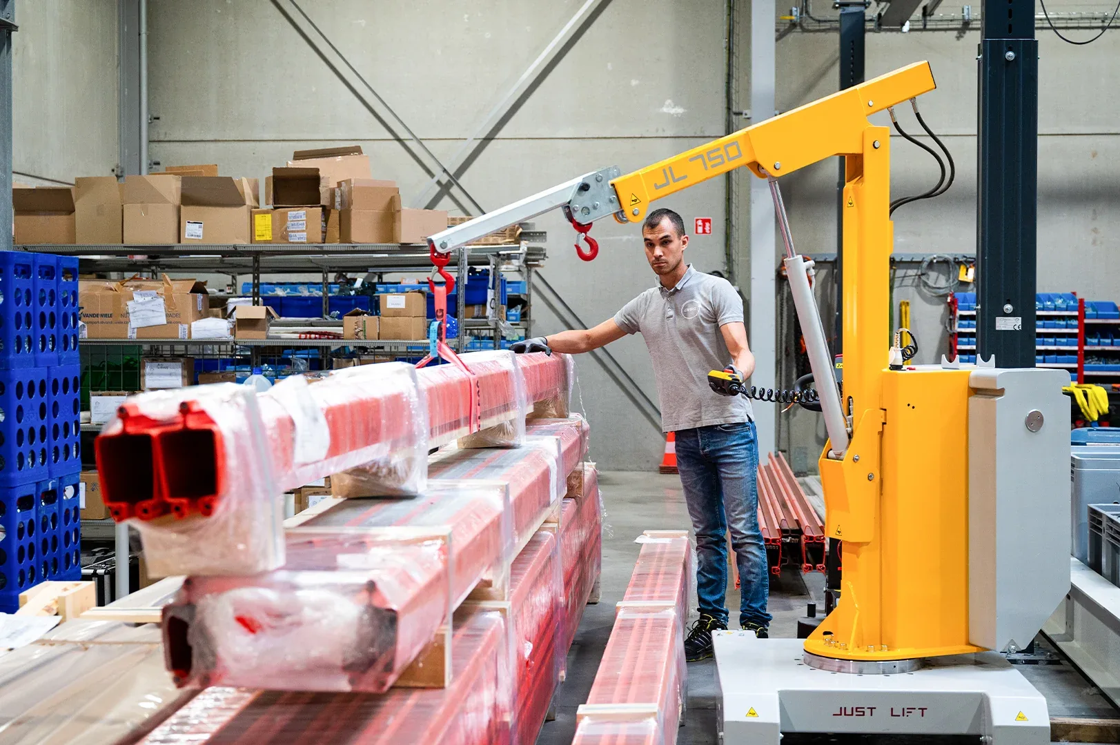 Just Lift JL750 mini crane lifting long packed profiles in a warehouse, operated with a wired pendant control