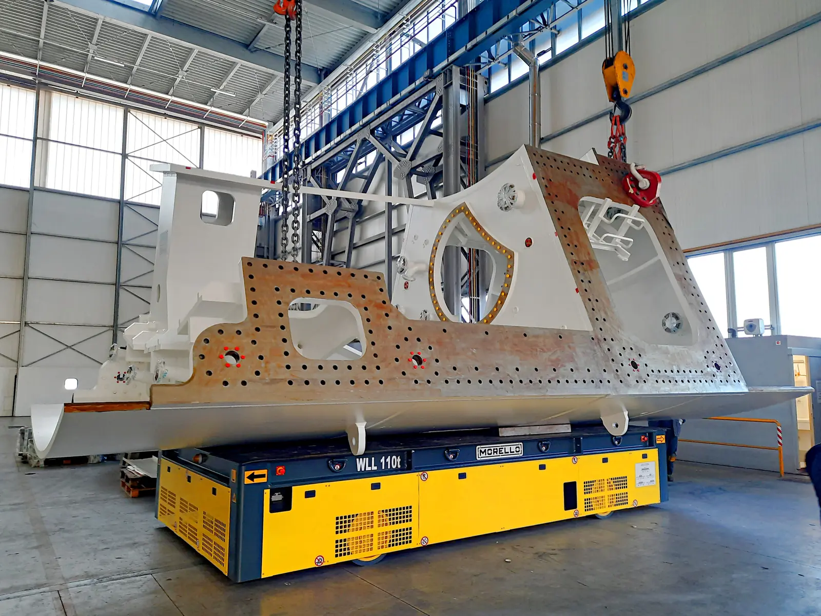Large machine frame lowered by crane onto a Morello SGAI cart