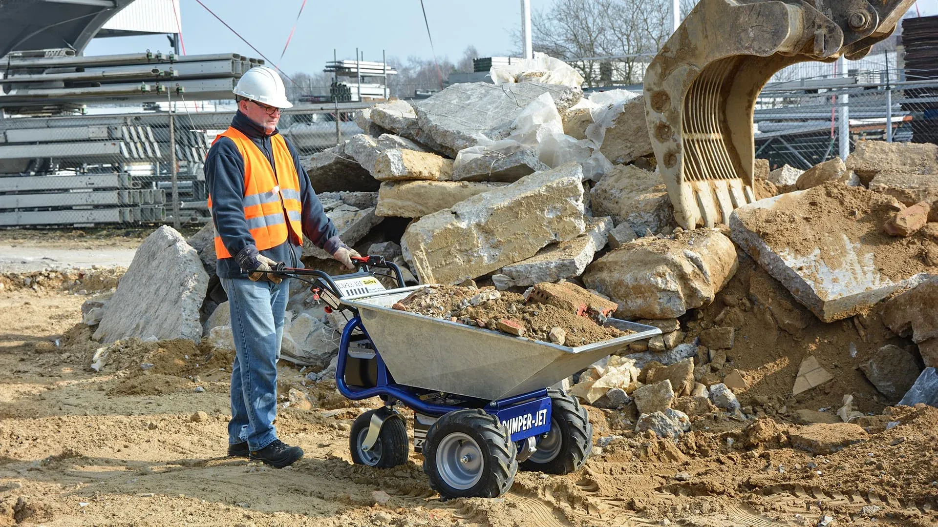 Worker hauling rubble with a Zallys DUMPER-JET electric wheelbarrow on a construction site