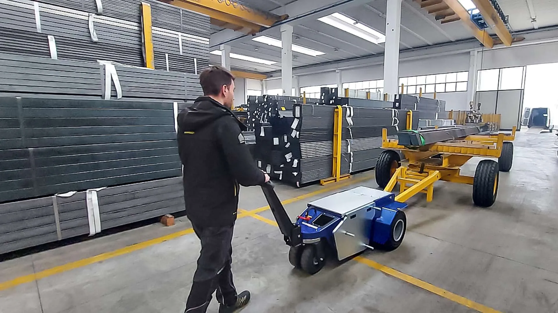 Zallys M10 electric mover towing a trolley loaded with long metal profiles